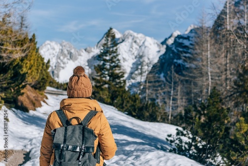 Rear shot of a woman with a backpack hiking in the snowy mountains of the Julian Alps in Slovenia