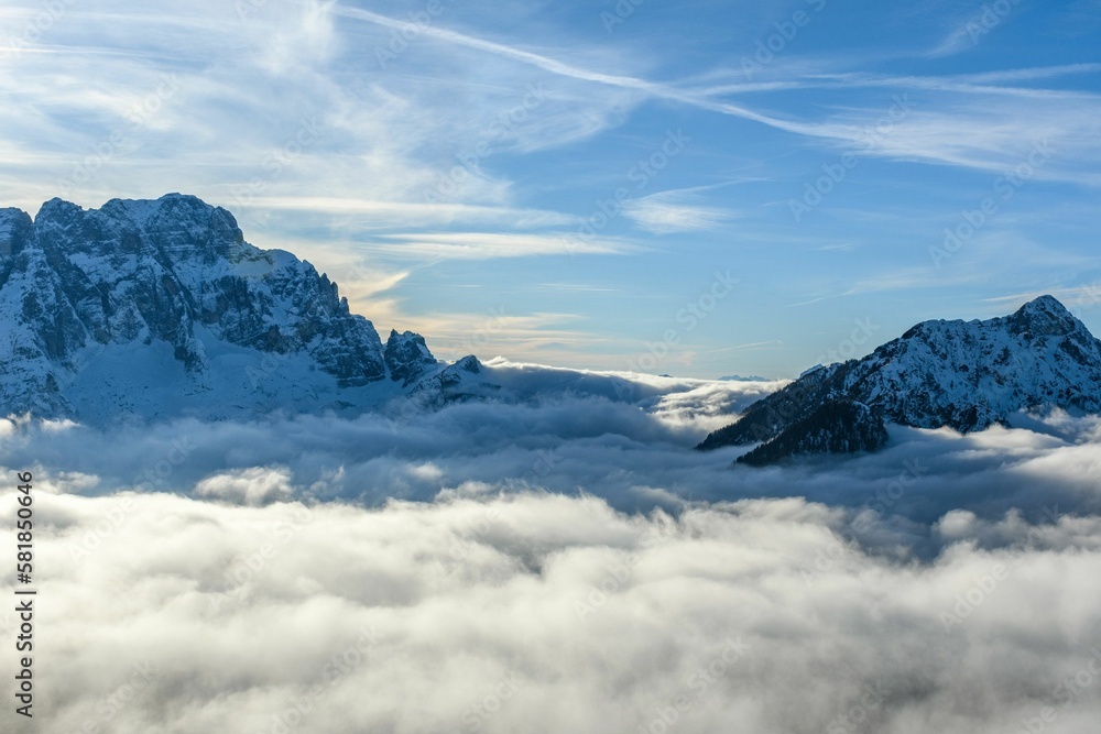 Gorgeous landscape with the snowy peaks of tall mountains emerging from a sea of foggy clouds
