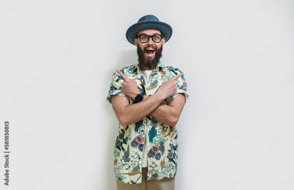 Portrait of positive man in hat and Hawaiian shirt standing with crossed arms and pointing to ad copy space on both sides. Isolated on white studio background Portrait of positive man in hat and Hawaiian shirt standing with crossed arms and pointing to ad copy space on both sides. Isolated on white studio background