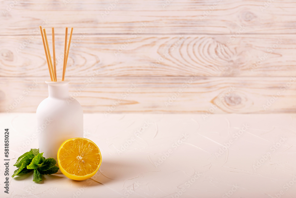 Perfume for the home. Aromatic reed diffuser with sticks, lemon and mint on light background. The concept of calm, relaxation and pleasure. Selective focus. Defocus Perfume for the home. Aromatic reed diffuser with sticks, lemon and mint on light background. The concept of calm, relaxation and pleasure. Selective focus. Defocus