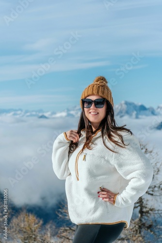Vertical shot of female with winter clothes,posing in front of alpine landscape on sunny winter day