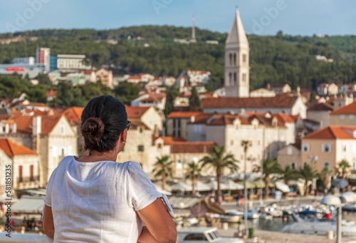 girl looking at idyllic coastal town of Supetar on Braa island in Croatia in the summer photo