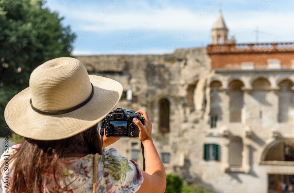 Girl in hat holding camera, taking photos of Diocletian's palace in Split, Croatia