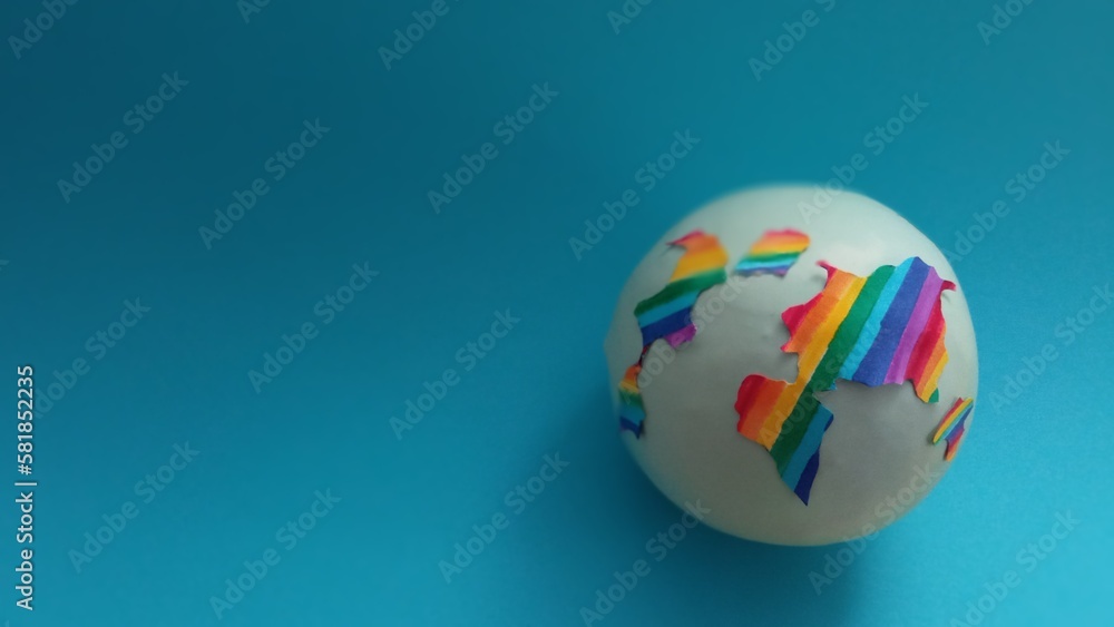 The globe is painted in rainbow colors on a blue background with space for text. The diversity of the earth. LGBT topics. Sex education. The topic of tolerance