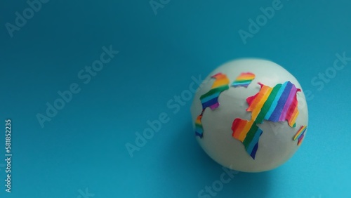 Obraz na płótnie The globe is painted in rainbow colors on a blue background with space for text. The diversity of the earth. LGBT topics. Sex education. The topic of tolerance w salonie