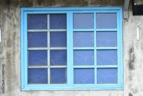 old blue wooden window with shutters on the white mottled wall