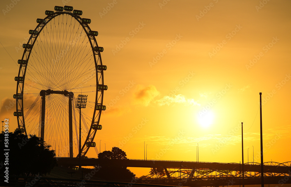 Amazing sunrise photo in Singapore, sun through Singapore big wheel silhouette landmark view to Helix bridge.