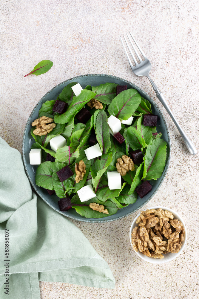 Beetroot salad with feta cheese, chard and walnuts on a pink background. Top view. 