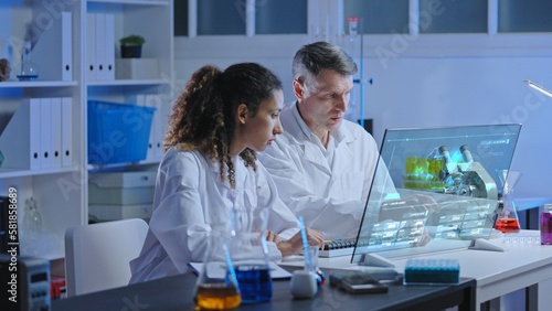 Two chemists studying chemical reaction simulation on holographic screen in modern lab