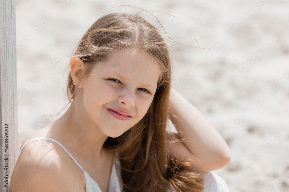 portrait of a little girl with long hair in a summer dress sitting on the beach portrait of a little girl with long hair in a summer dress sitting on the beach