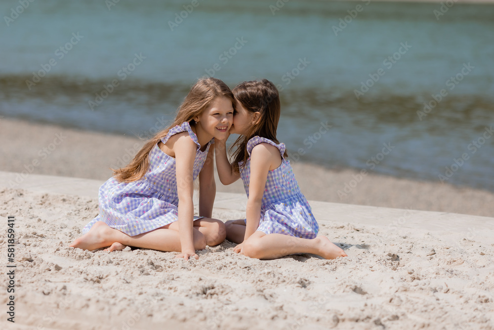 happy little girls with long hair play on a sandy beach near the sea on a sunny day. Children's Day.Space for text happy little girls with long hair play on a sandy beach near the sea on a sunny day. Children's Day.Space for text