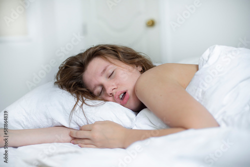 young girl sleeps in the morning in bed and snores loudly with her mouth open, the concept of person have problem with sleep and breathing