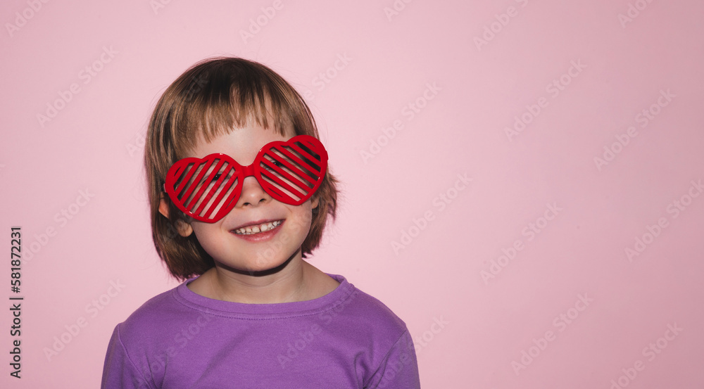 Smiling girl in heart shaped glasses on pink background. Concept of love, joy, happiness and life. Copy space Smiling girl in heart shaped glasses on pink background. Concept of love, joy, happiness and life. Copy space