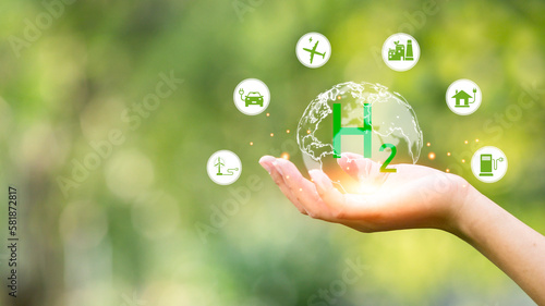 Human hand holding green earth environment hydrogen energy icon with icons