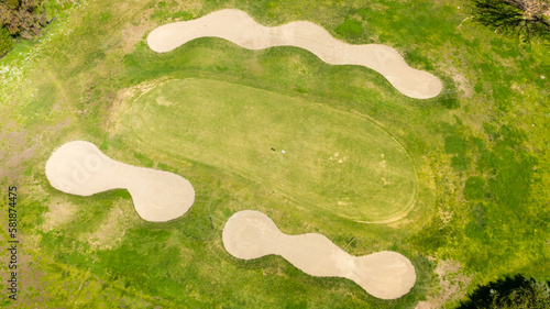 Aerial view of an empty golf course with green hills and sand bunkers. The sports club is empty and nobody is playing. Sports concept.