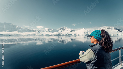 Female Tourist On Luxury Antarctica Cruise Ship Looking Out At The Stunning Scenic Arctic Landscape, Leaning on Bow Railing, Landscape Shot