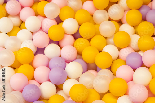 a lot of orange, lilac and pink balls in a dry pool in the game room