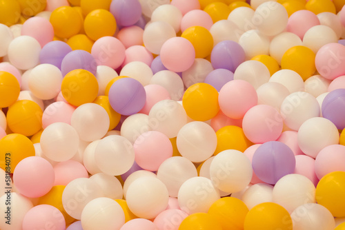 a lot of orange, lilac and pink balls in a dry pool in the game room