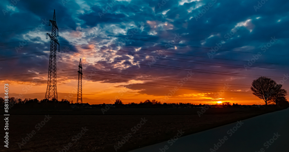 Sunset with a dramatic sky and overland high voltage lines near Tabertshausen, Bavaria, Germany Sunset with a dramatic sky and overland high voltage lines near Tabertshausen, Bavaria, Germany