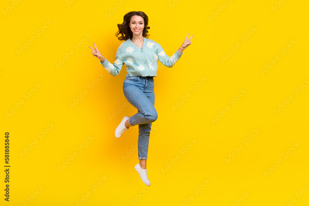 Full body photo of overjoyed cheerful lady jumping hands fingers demonstrate v-sign isolated on yellow color background