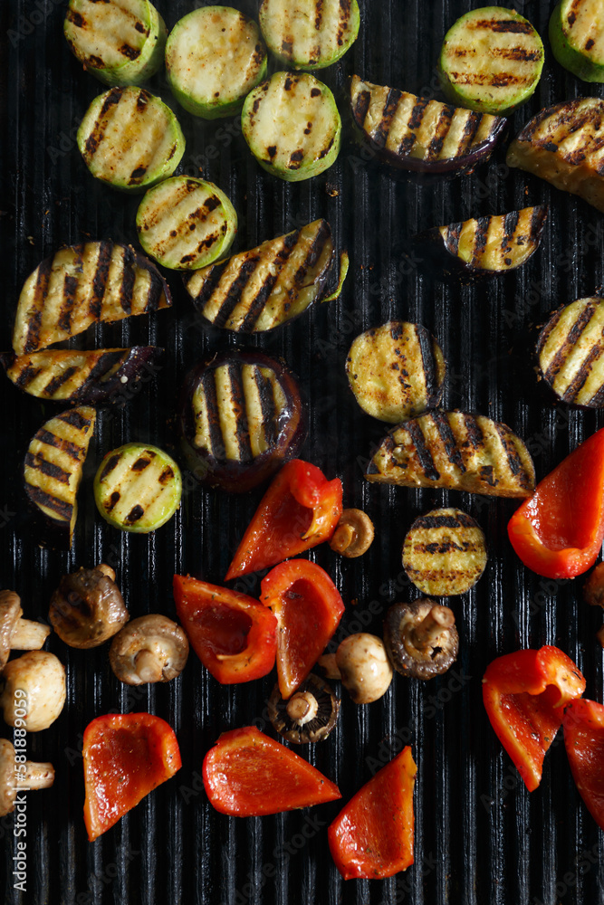 Grilled vegetables in flat lay. Hot grill pan surface with cooked zucchini, red bell pepers and mushrooms