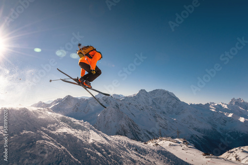 winter vacation at the ski resort. skier quickly fly in the air doing a stunt heli-skiing on the background of snow-capped mountains