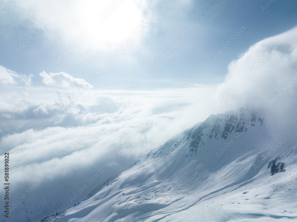 Alpine landscape with peaks covered by snow and clouds. Magical clouds covering peaks of the mountains at the famous St. Anton am Arlberg ski resort. Alpine landscape with peaks covered by snow and clouds. Magical clouds covering peaks of the mountains at the famous St. Anton am Arlberg ski resort.