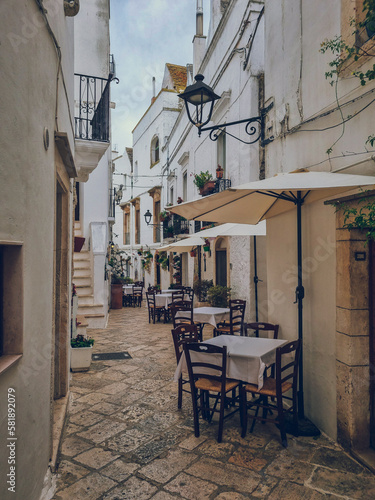 Charming white tiny street with a restaurant at the small town of Locorotondo, Puglia, Italy, Italia