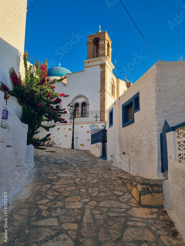 Mediterrenean white and blue facades with a church in the background at sunset in the Dodecanese Island of Lipsi, Greece