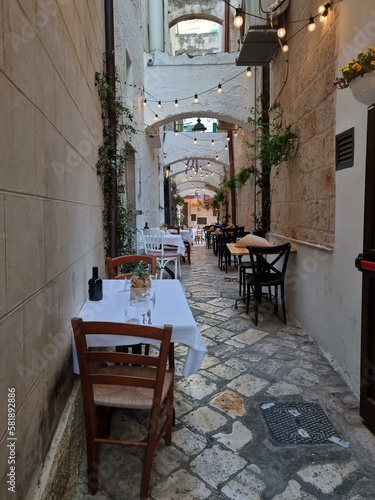 Charming white tiny street with a restaurant at the coastal Italian town of Monopoli, Puglia, Italy, Italia
