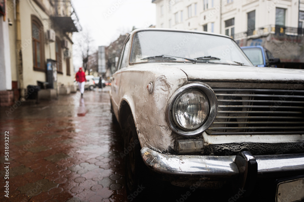 Old vintage car headlight in rain city street.