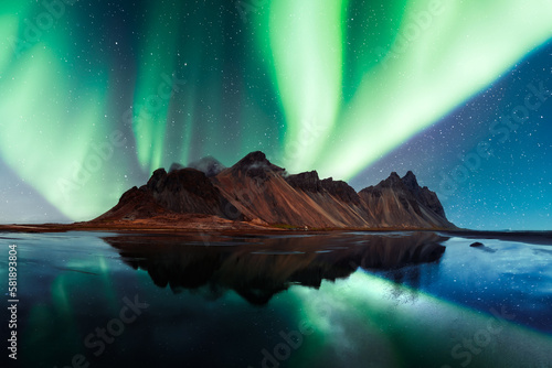 Foto Aurora borealis Northern lights over famous Stokksnes mountains on Vestrahorn cape
