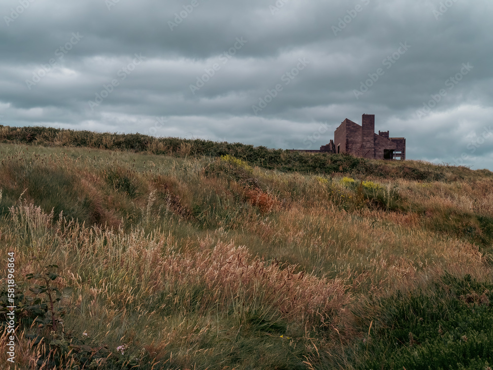 A ruined building under a beautiful dramatic sky. The harsh nature of Northern Europe. landscape of Ireland. Green grass field under cloudy sky
