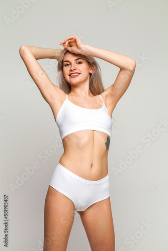 Young beautiful girl in sports underwear isolated on gray background