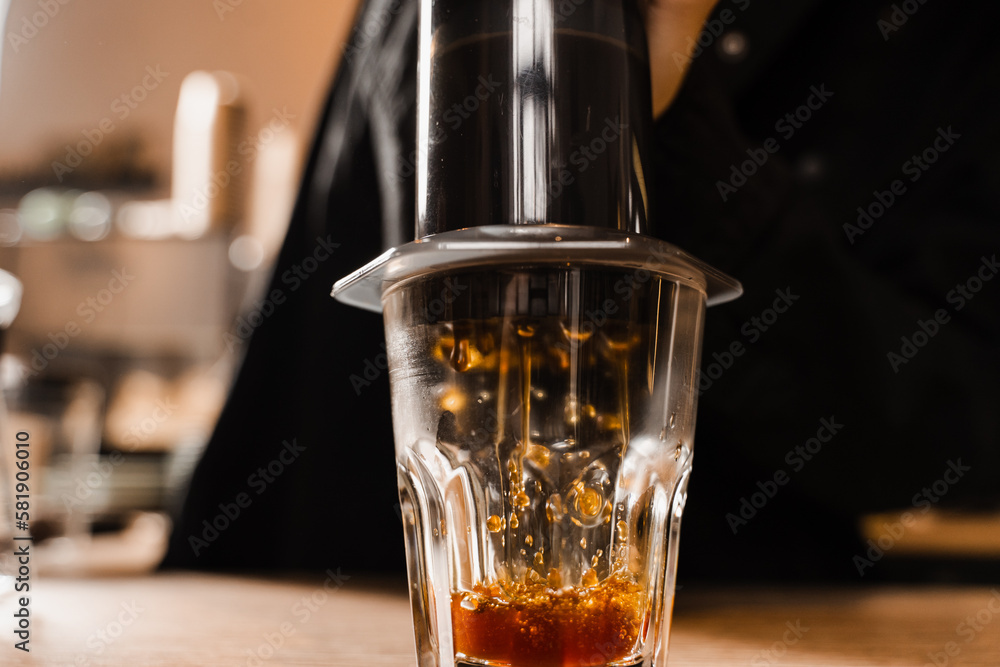 Aeropress coffee. Process of pouring coffee in cup. Barista is pushing aeropress for pouring coffee drops. Falling coffee drops in cup close-up. Aeropress coffee. Process of pouring coffee in cup. Barista is pushing aeropress for pouring coffee drops. Falling coffee drops in cup close-up.