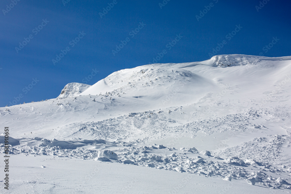 The aftermath of an avalanche leaves behind a snowy, rocky terrain.
