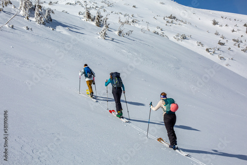 Against the snow-covered mountain, a group of skiers begin their ascent, their energy and excitement palpable as they venture into the winter wilderness