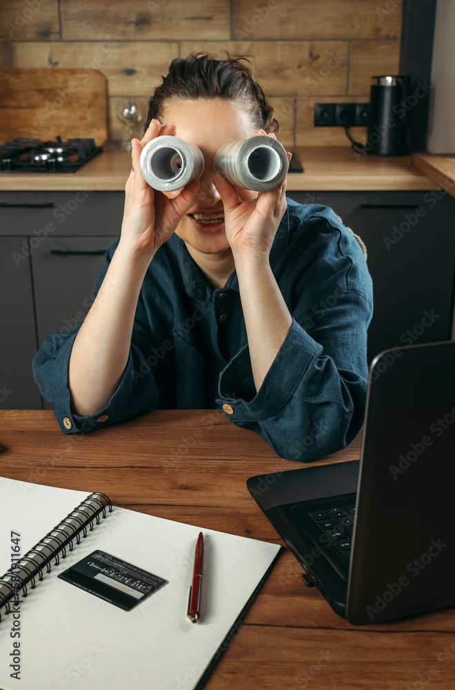 Portrait of a female clothing stylist who sits at a table near a laptop and looks through large spools of thread. Portrait of a female clothing stylist who sits at a table near a laptop and looks through large spools of thread.