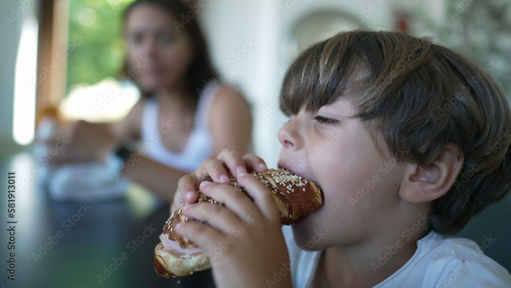 Little boy eating sandwich. Child taking a bite of bread. Kid eats delicious carb food