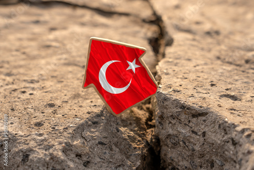 Earthquake in Turkey. The flag of Turkey in the form of a house standing on a broken slab with cracks. The idea of ​​a devastating earthquake in Turkey.