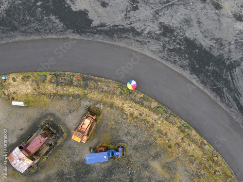 Aerial view of a busy construction site from a high angle, showing the road below with a lonely person under an umbrella for scale.