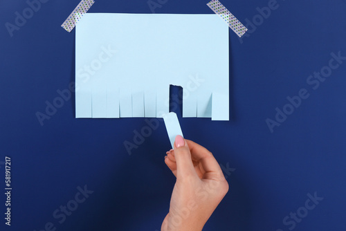 Woman tearing off paper ad on blue background photo