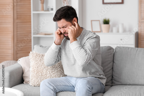 Foto Young man suffering from loud noise at home