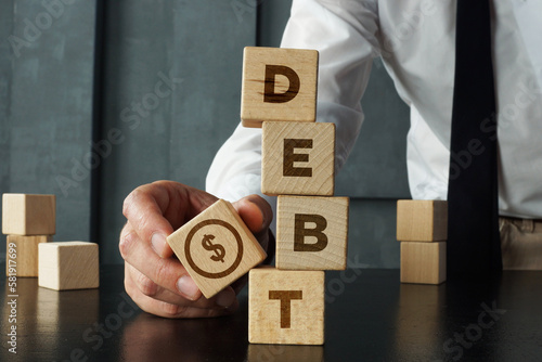 Foto Debt is shown by wooden blocks with the word and the image of dollars
