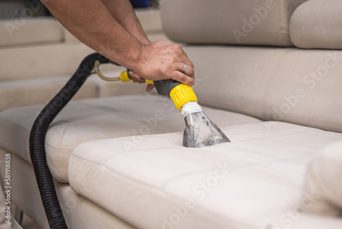 Cleaning a dirty sofa with a sofa washer. Close up of hands holding sofa cleaner. Professional sofa wash. Sofa wash image