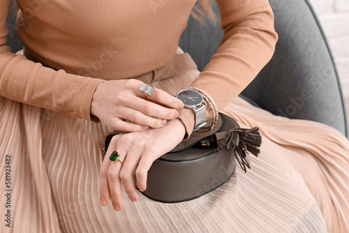 Woman with stylish wristwatch sitting at home, closeup photo