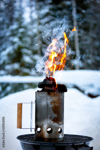 Barbecue starter with coals and open fire against the backdrop of a winter forest