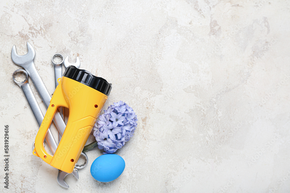 Wrenches with flashlight, Easter egg and hyacinth flower on grunge background