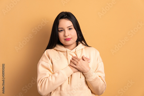 confident caucasian woman hands over heart, chest in studio shot. care, love, affection, support concept. photo