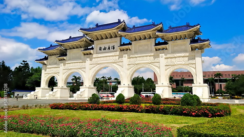 National Chiang Kai-shek Memorial Hall Square, Taipei, Taiwan - July 16, 2017: front gate of the memorial hall under bright blue sky and flowers and meadow in the front